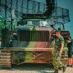 Military vehicle with camouflage, radar system, and soldier in uniform.