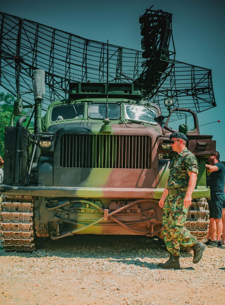 Military vehicle with camouflage, radar system, and soldier in uniform.