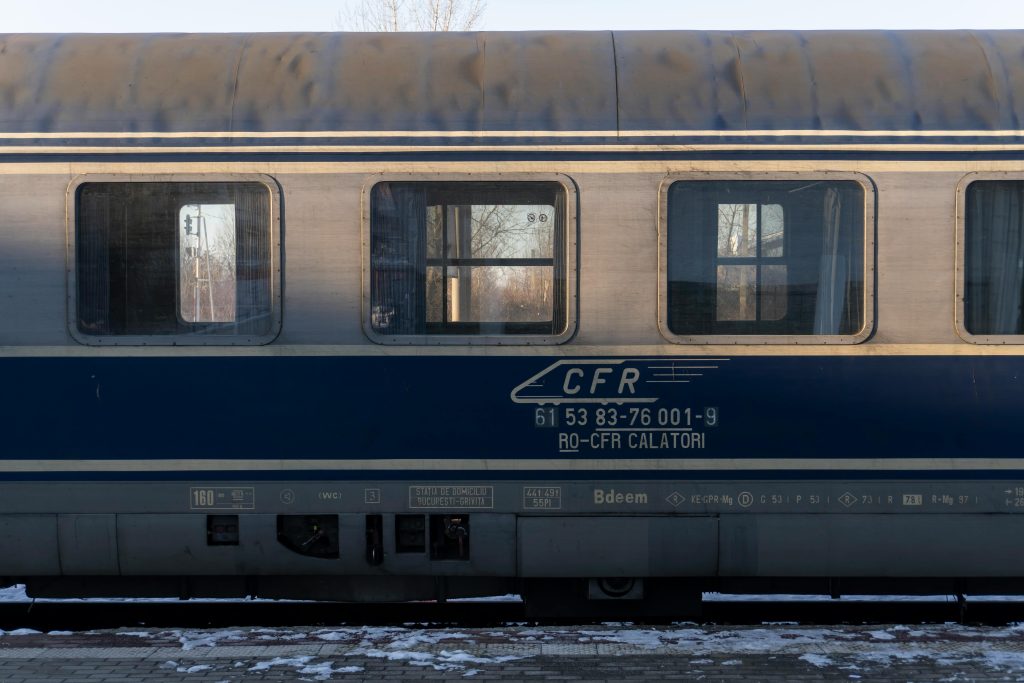 Side view of a passenger train carriage at a railway station with snowy ground.