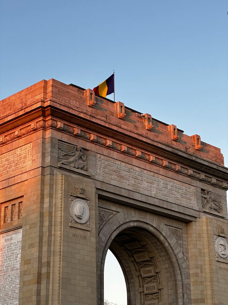 The Triumphal Arch in Bucharest, Romania, bathed in warm sunset light, showcases exquisite architecture.