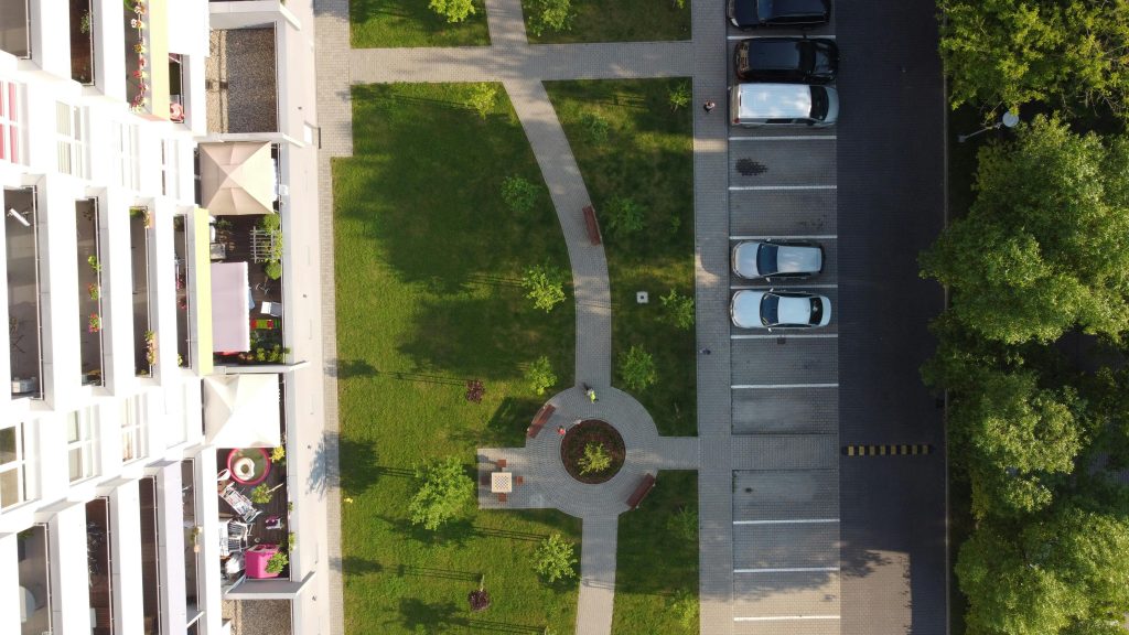 Aerial photo of a residential complex with green areas and parking in Łódź, Poland.