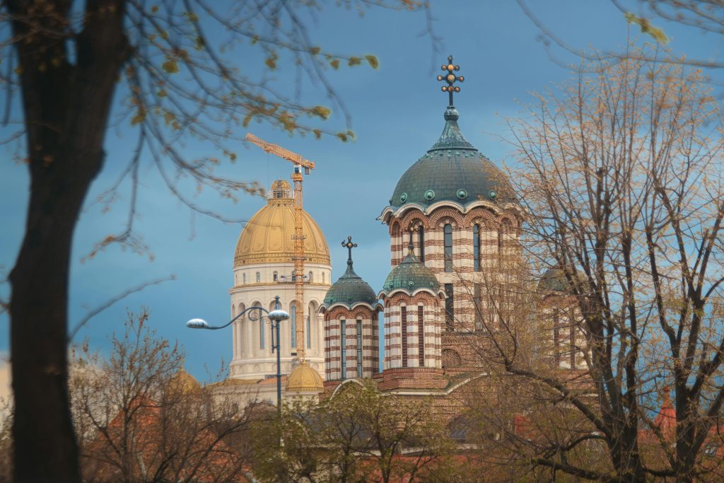 Scenic view of elegant church domes in Bucharest, surrounded by trees under a clear sky.