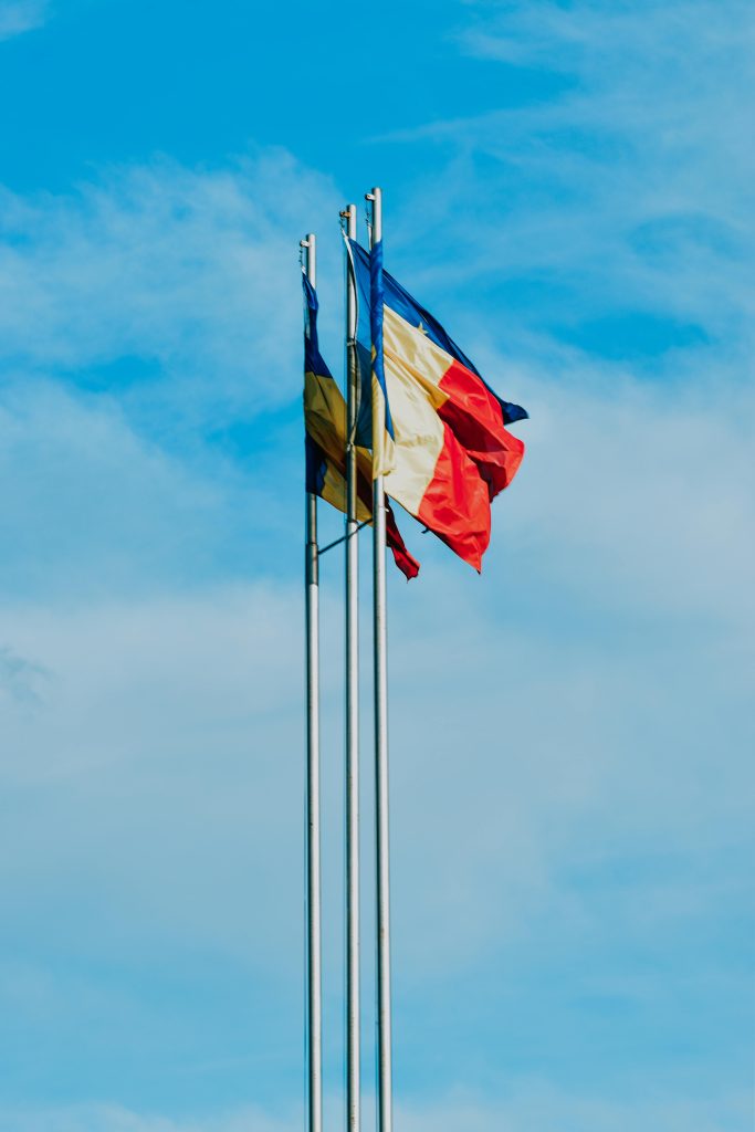 From below of waving flags of France Moldavia and Europe symbolizing unity of European countries placed against blue sky