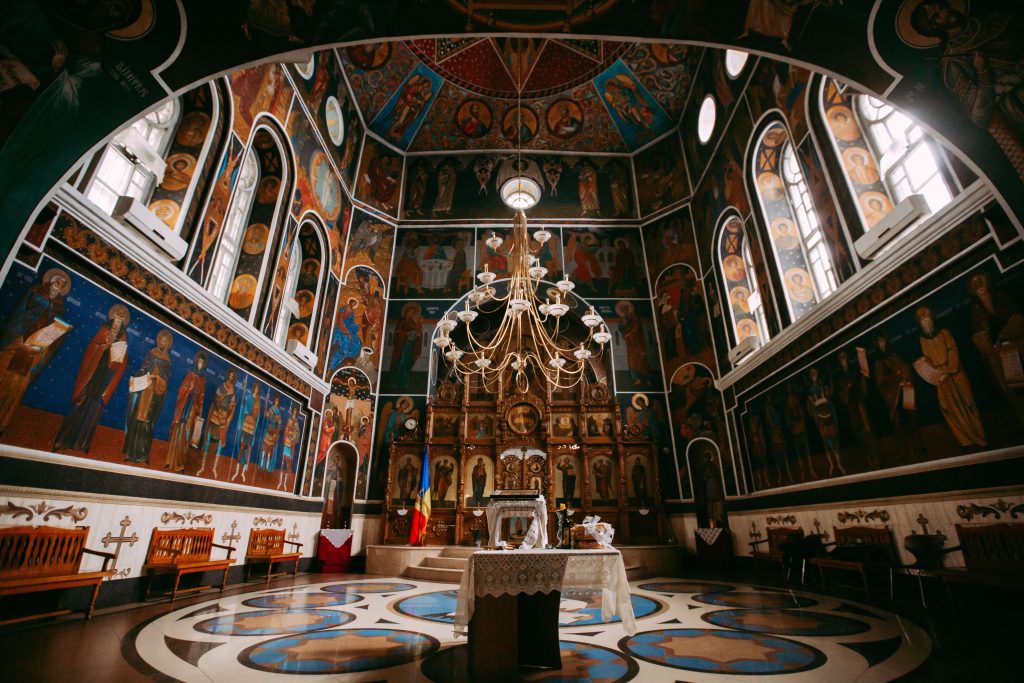 Beautifully adorned church interior with vintage murals and grand chandelier.