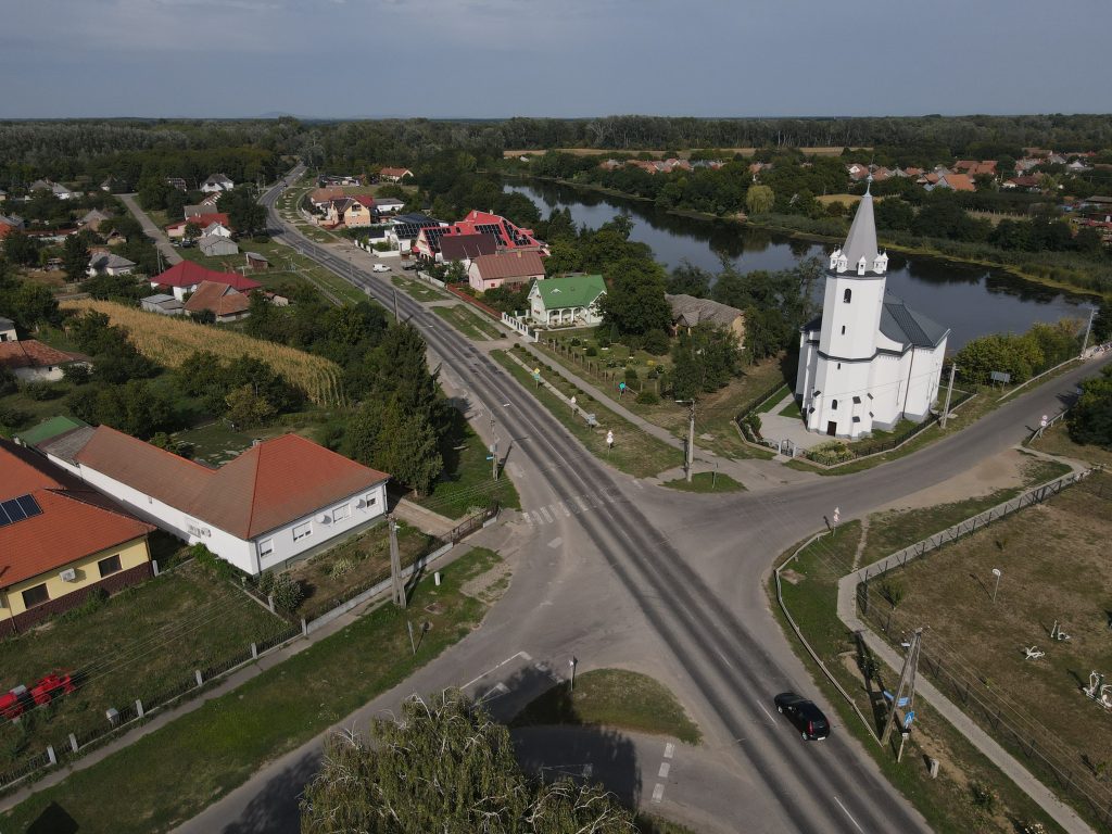 Aerial shot of the picturesque church and river in Tunyogmatolcs, Hungary, showcasing rural charm.